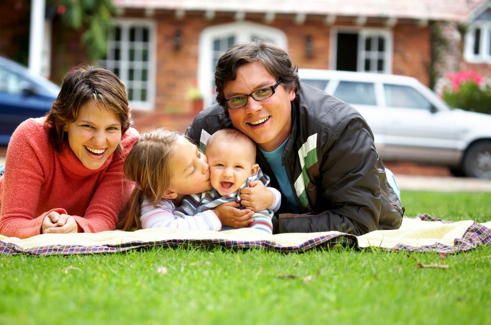 happy family smiling in a portrait of a mum and dad with their two kids